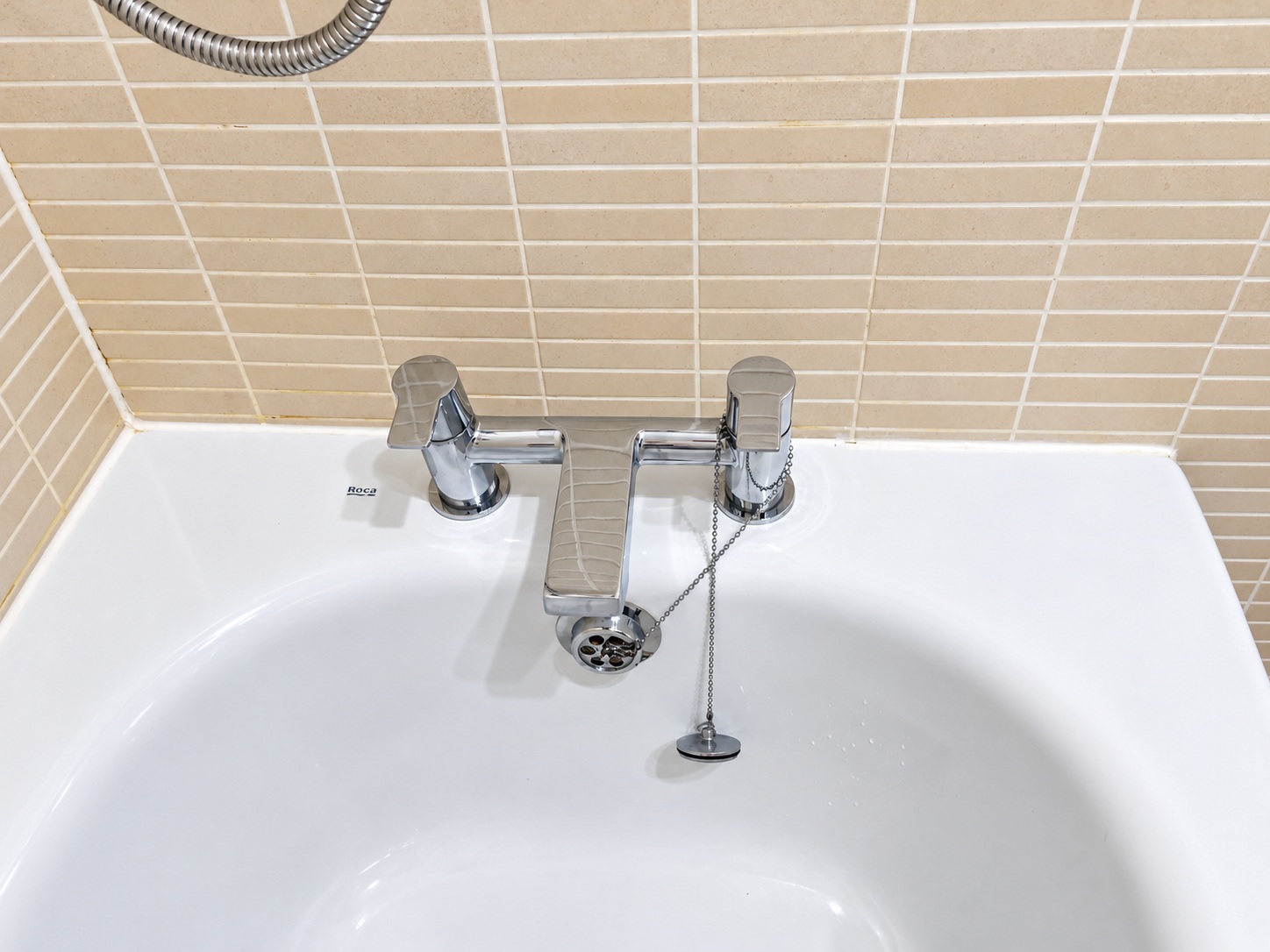 Chrome bath mixer taps and tiled surround after cleaning