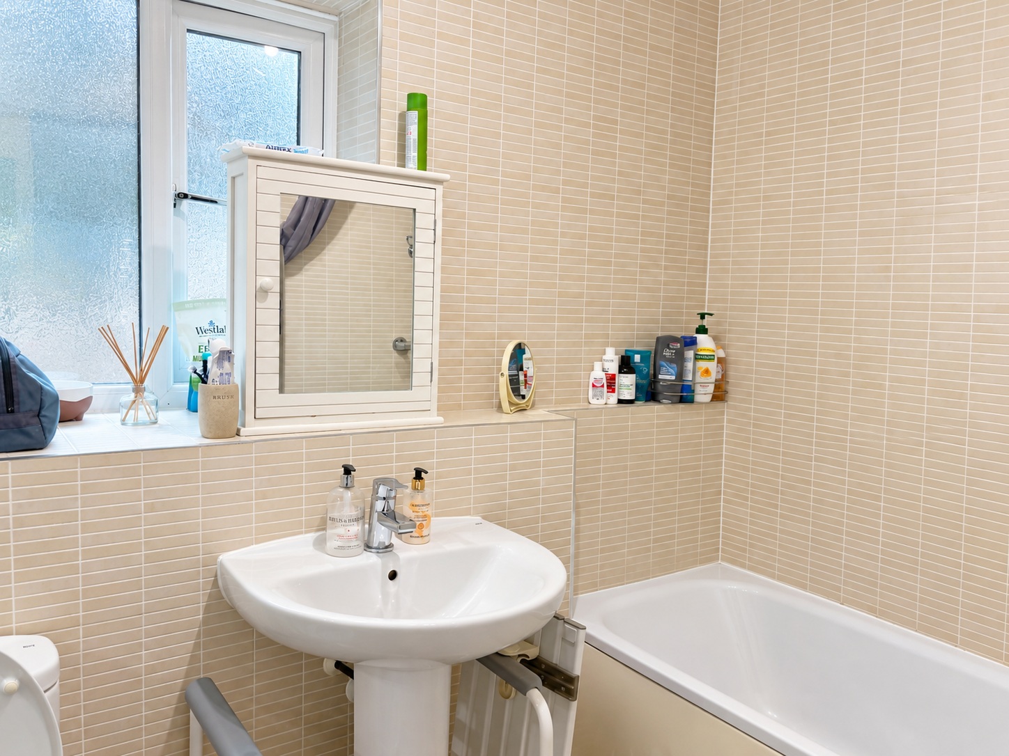 The same bathroom after cleaning, showing basin, tiled walls and bath