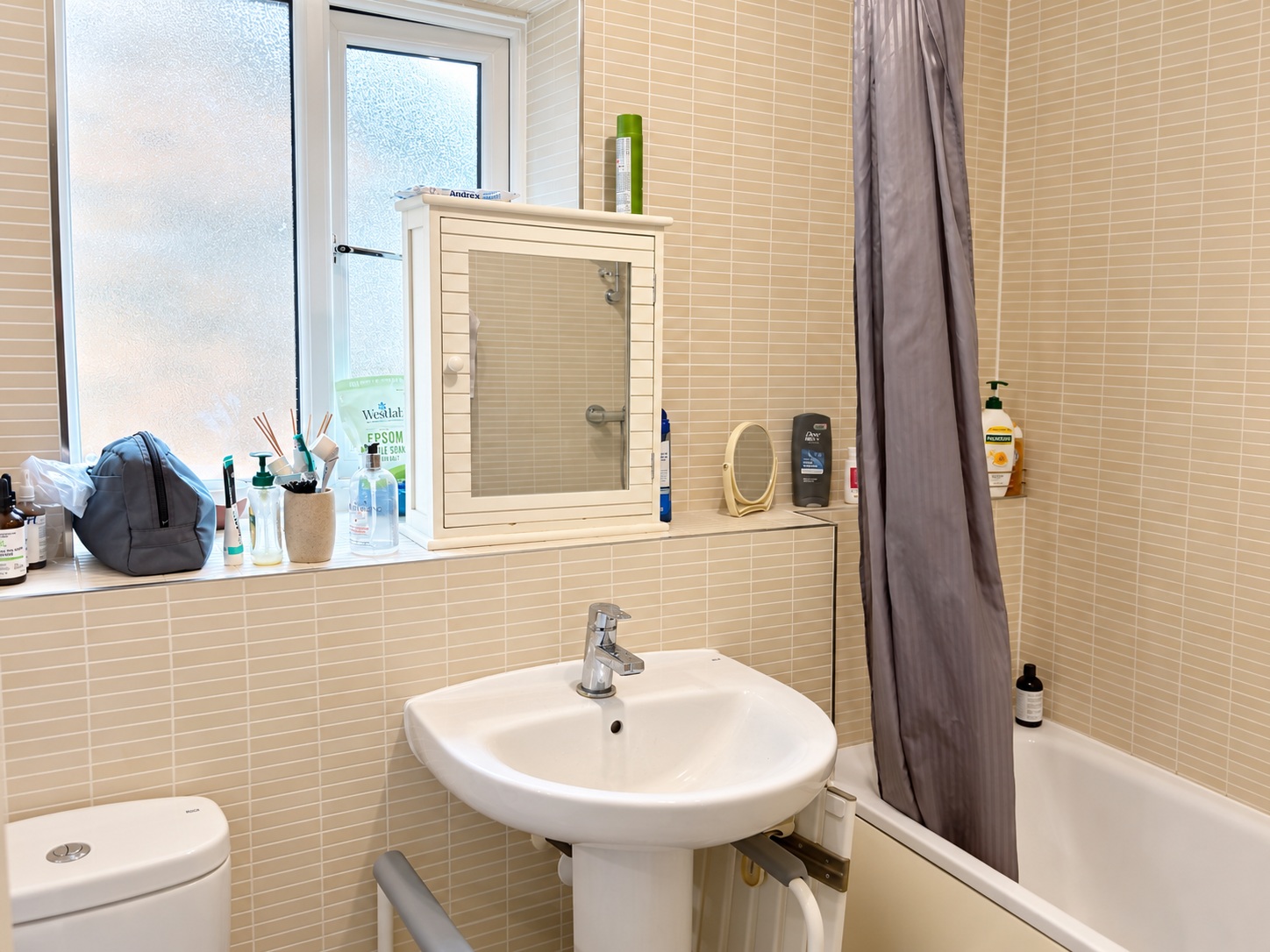 Bathroom before cleaning, with original toiletries and shower curtain visible