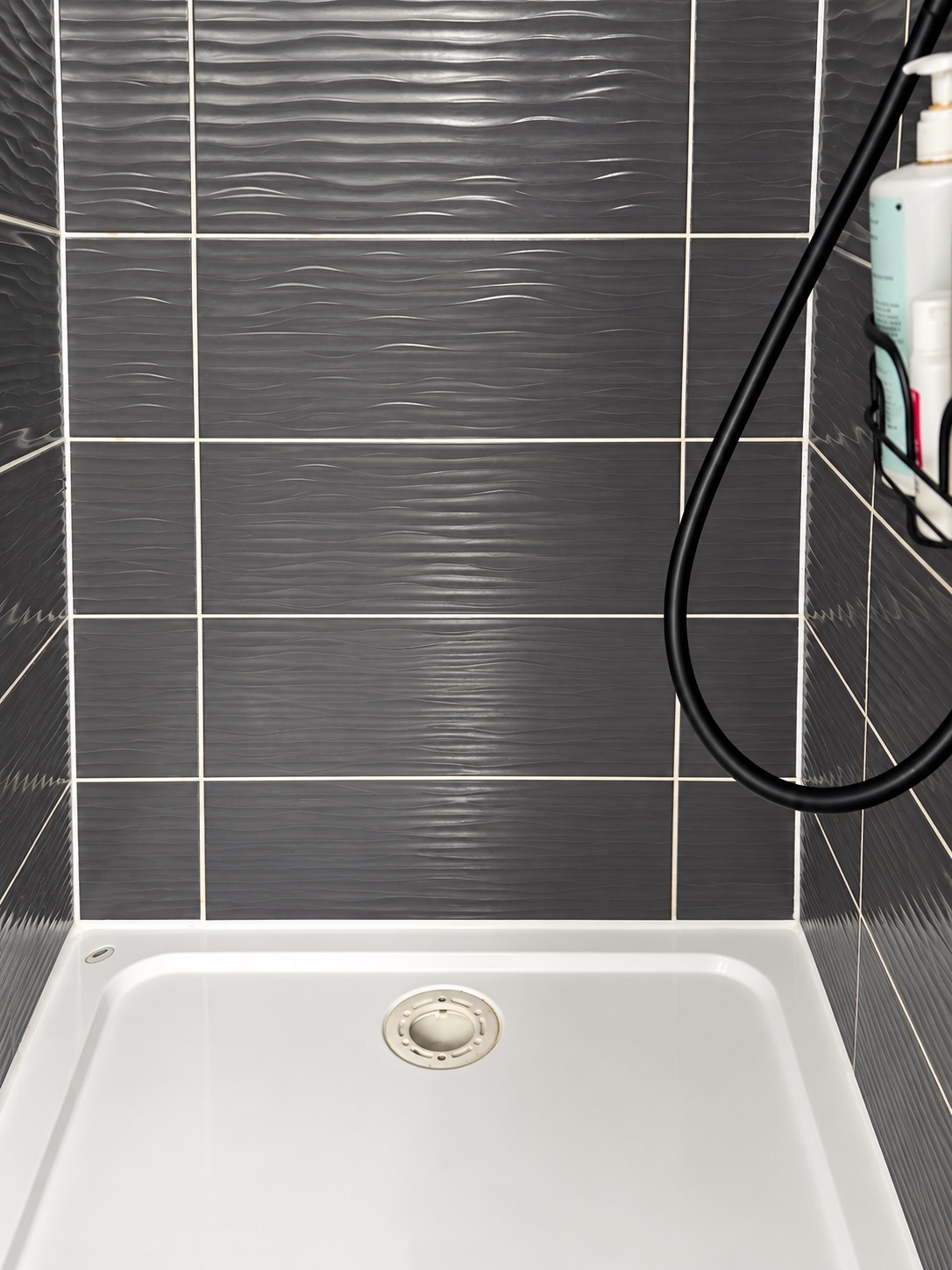 Shower tray and dark tiled enclosure following cleaning