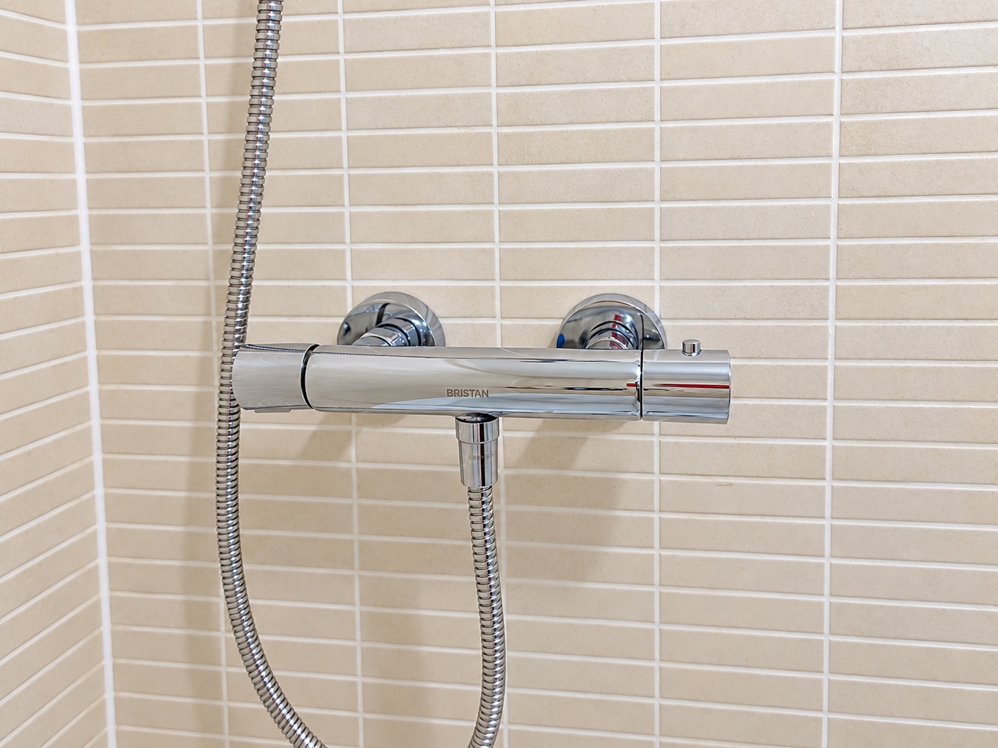 Chrome shower controls and original beige tiled wall after cleaning